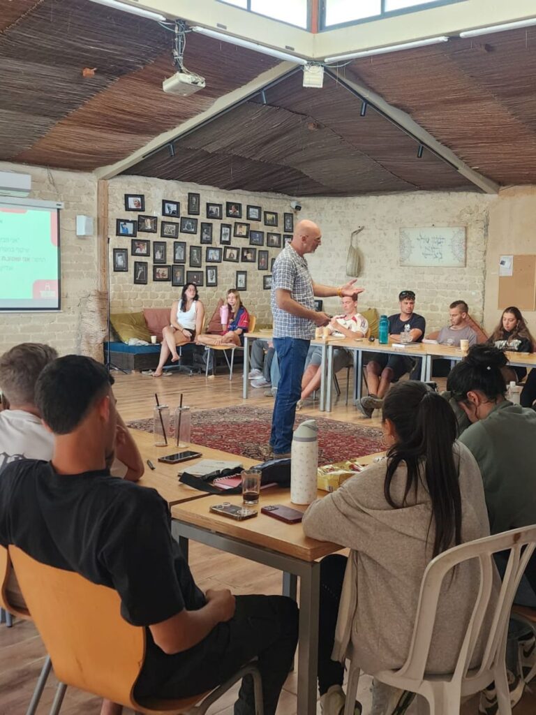 אביעד פאר מנחה מפגש עם קבוצת צעירים סביב שולחנות